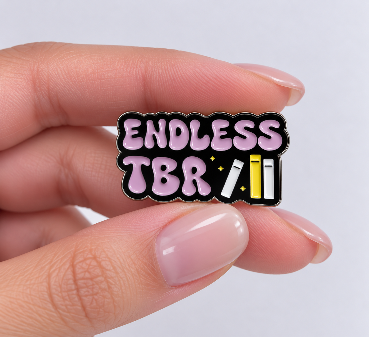 Close-up of Endless TBR bookish pin in hand