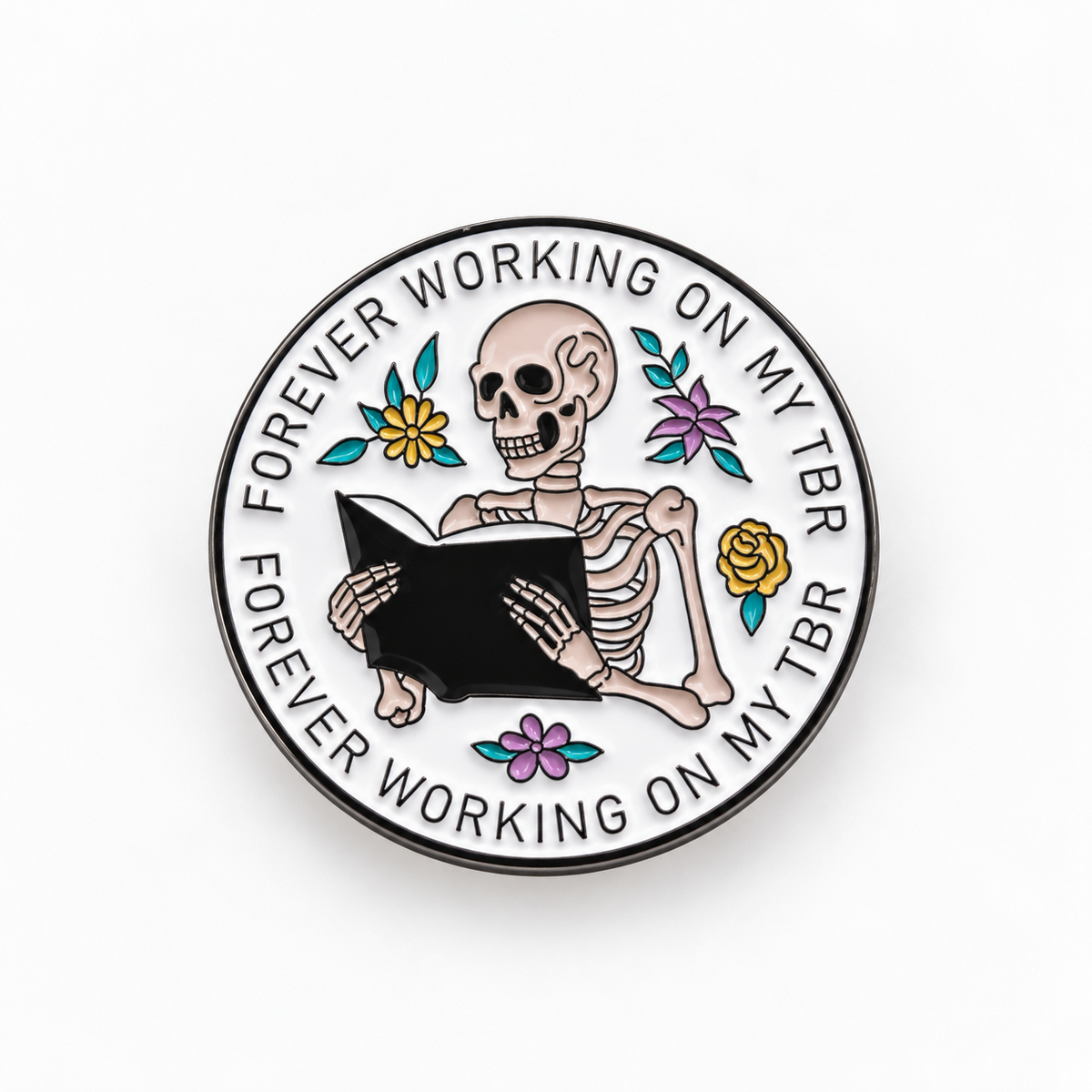 Forever Working on My TBR round enamel pin with a skeleton reading a book and flowers