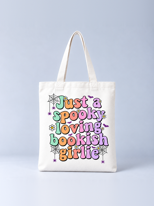 Just a Spooky Loving Bookish Girlie Halloween tote bag, front view – cream canvas tote with pastel bubble lettering, spider webs, bats and daisies print