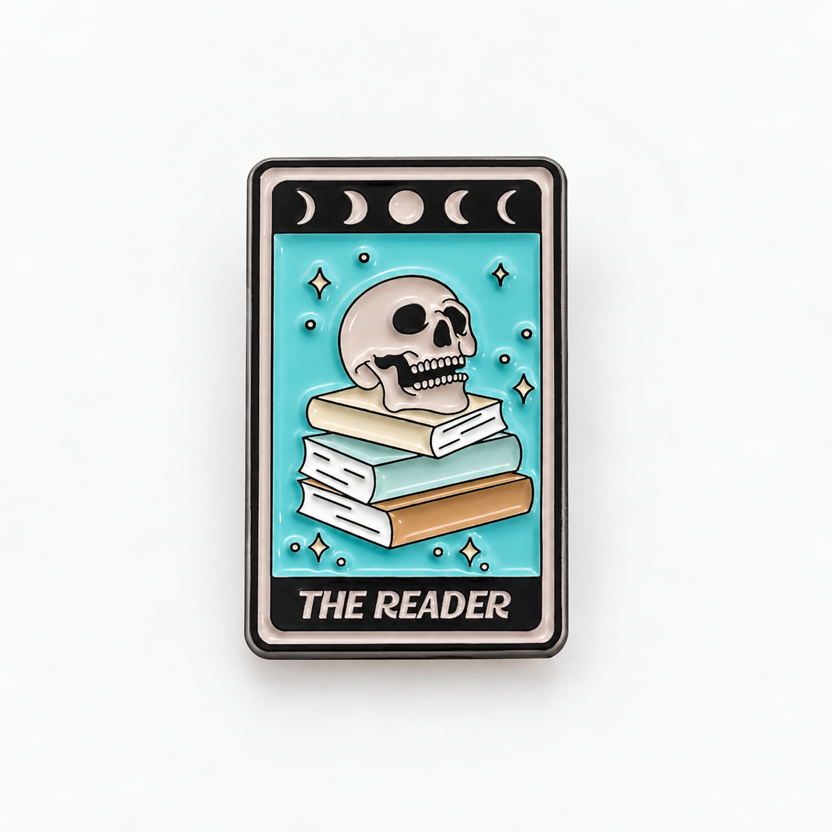 The Reader tarot card enamel pin with a skull on a stack of books and moon phases, bookish pin