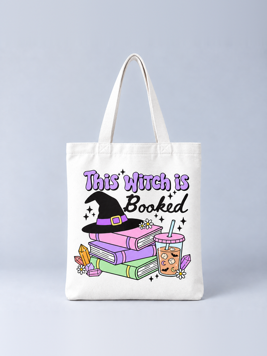 This Witch Is Booked Halloween tote bag, front view – cream canvas tote with a witch hat on a stack of pastel books, iced coffee and crystals print